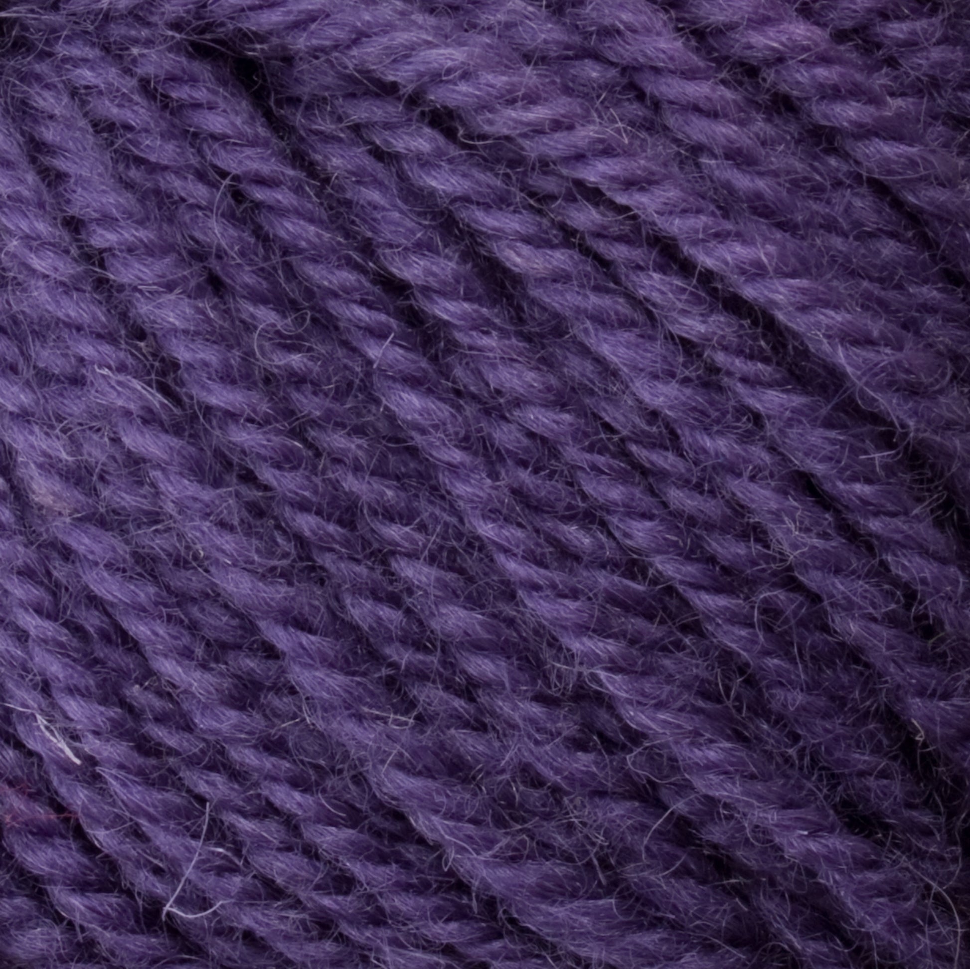 Close-up image of Halcyon Deco Rug Wool yarn by Caledonian Dye Works, showcasing the thick, twisted fibers and their detailed 100% wool texture in a purple hue.