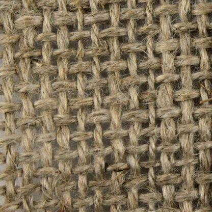 Close-up of a coarse, beige Unbleached Linen Rug Backing 64" from Dorr Fabrics Inc. The image showcases the interwoven fibers in a crisscross pattern, highlighting the rough and natural appearance of the burlap-like material.