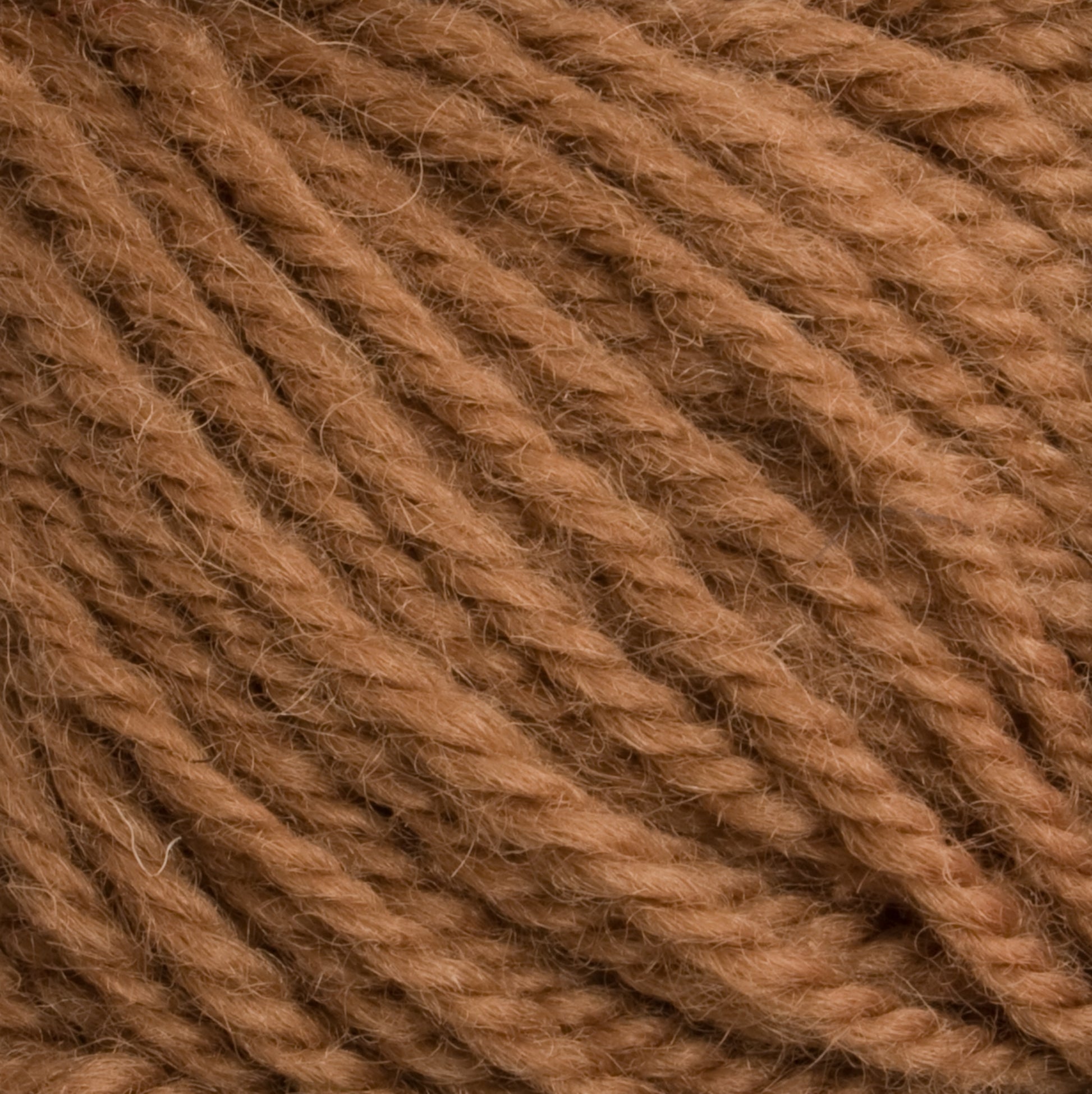 Here is a close-up image of Halcyon Deco Rug Wool by Caledonian Dye Works, showcasing brown yarn with tightly twisted fibers and a slightly fuzzy texture. The strands are uniformly wound, giving it a dense and soft appearance perfect for knitting or crocheting projects. Made from 100% wool, this versatile yarn combines durability with elegance.