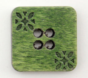 The Wood Square 3/4" Button by Buttons Etc. is a green, square-shaped button with a wooden texture, featuring four centrally arranged holes in a square pattern. The button is adorned with decorative floral-like carvings in two opposite corners and has softly rounded edges, providing an intricate and delicate etched design detail to its surface.