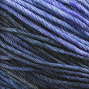 Close-up of multiple strands of Malabrigo Rios by Malabrigo Yarn in shades of blue and purple, from light lavender to deep navy. The soft, slightly fuzzy texture captures the intricate details of the superwash yarn fibers, showcasing the exquisite kettle-dyed colors.