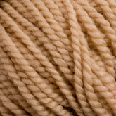 Close-up image of Norumbega, a beige-colored, thickly twisted yarn. The texture of this Aran weight yarn from Caledonian Dye Works is prominent, showcasing tightly wound fibers with a soft and slightly fuzzy appearance. Made from 100% U.S. wool, it promises durable fabric perfect for cozy sweaters and blankets.