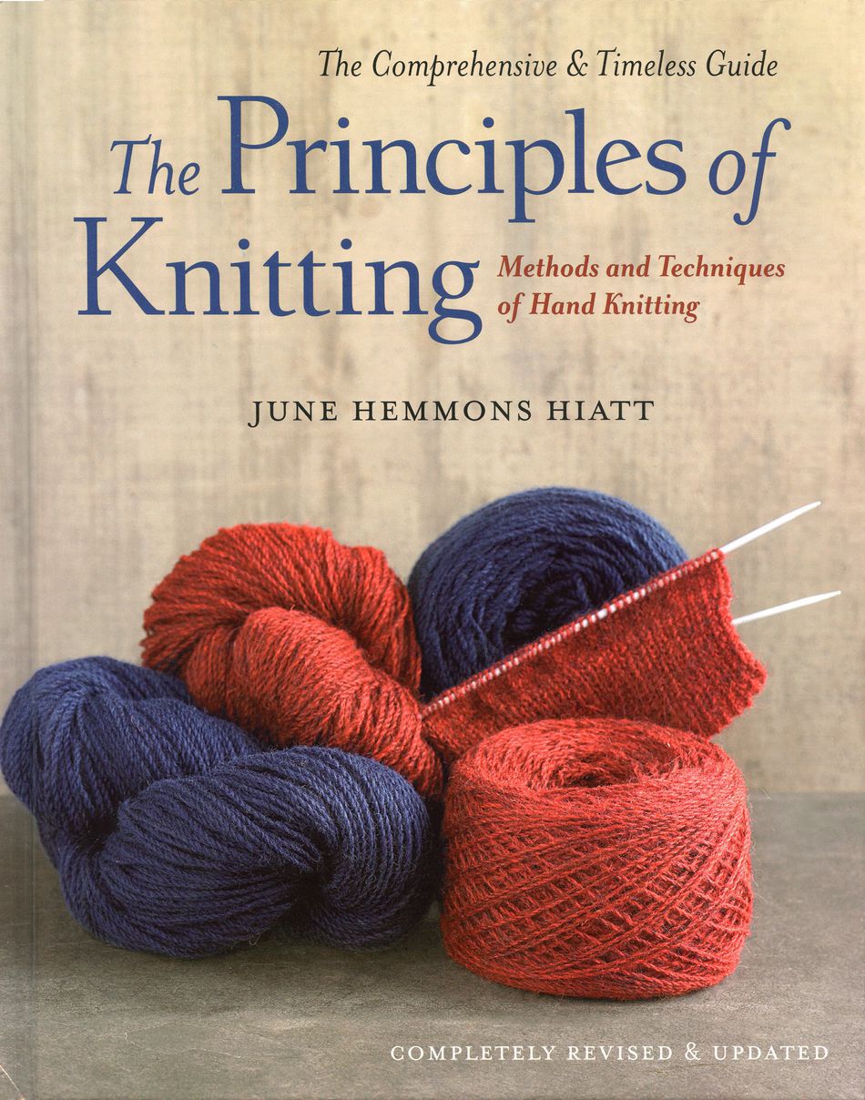 Cover of "The Principles of Knitting" by Ingram Content, displaying the book title in blue and red text on a beige background. Beneath the title are four skeins of red and blue yarn, with red yarn partially knitted on needles. The text indicates that it is a revised and updated comprehensive reference book.