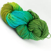 A twisted skein of Great Adirondack Organic DK Cotton yarn from Great Adirondack Yarn Co, Inc., featuring vibrant, hand-dyed variegated colors that transition seamlessly from shades of green to bright blue. The texture is soft and smooth, with strands neatly coiled together against a plain white background.