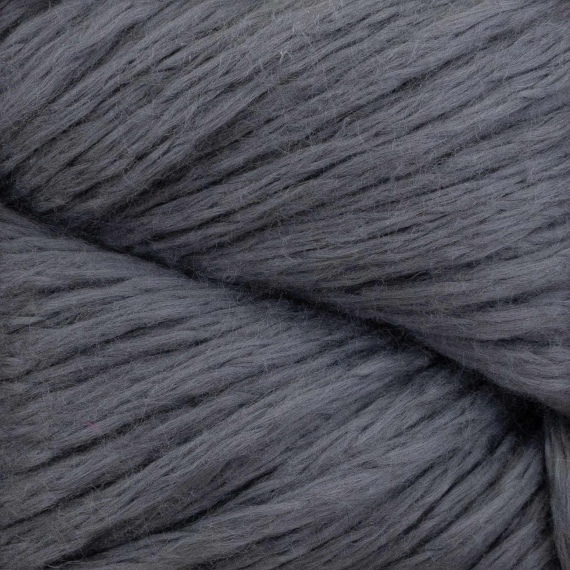 A close-up image of the Cumulus Cotton by Juniper Moon Farm reveals its soft, chunky gray yarn with fluffy, smooth fibers expertly twisted together, showcasing durable chainette construction. The even and consistent gray color throughout the entire strand makes it perfect for crafting weightless accessories.