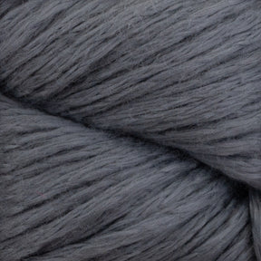 A close-up image of the Cumulus Cotton by Juniper Moon Farm reveals its soft, chunky gray yarn with fluffy, smooth fibers expertly twisted together, showcasing durable chainette construction. The even and consistent gray color throughout the entire strand makes it perfect for crafting weightless accessories.