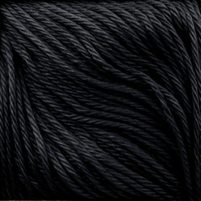 Close-up of a skein of Cascade Ultra Pima Cotton Yarn by Cascade Yarns. The black yarn is made from Peruvian Pima Cotton fibers that are tightly twisted, giving them a smooth and slightly shiny appearance. Known for its soft hand, the Cascade Ultra Pima Cotton Yarn ensures strands are uniform in thickness and neatly arranged, creating a textured pattern.