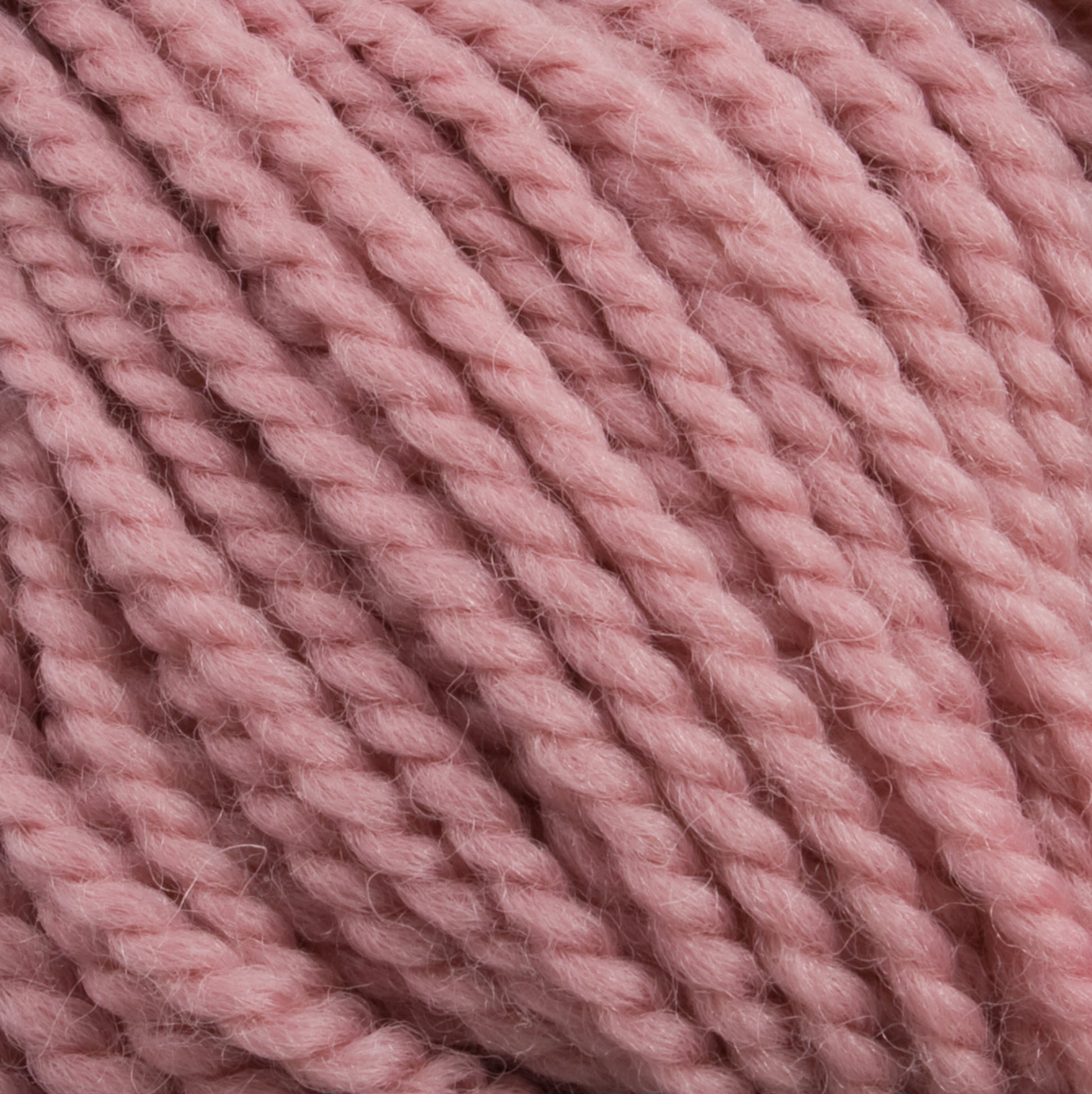 Close-up image of a ball of thick, twisted Norumbega yarn in a soft pastel pink color, showcasing its texture and fibers in detail. Ideal for weavers, this 100% U.S. wool yarn from Caledonian Dye Works promises both quality and beauty for your craft projects.