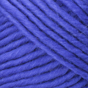 Close-up image of thick, soft, royal blue Lamb's Pride Bulky Yarn from Brown Sheep, showing detailed texture and individual fibers. The yarn is tightly wound in a spiral pattern, revealing its fluffy and slightly fuzzy nature—perfect for knitters and crocheters crafting Icelandic sweaters.