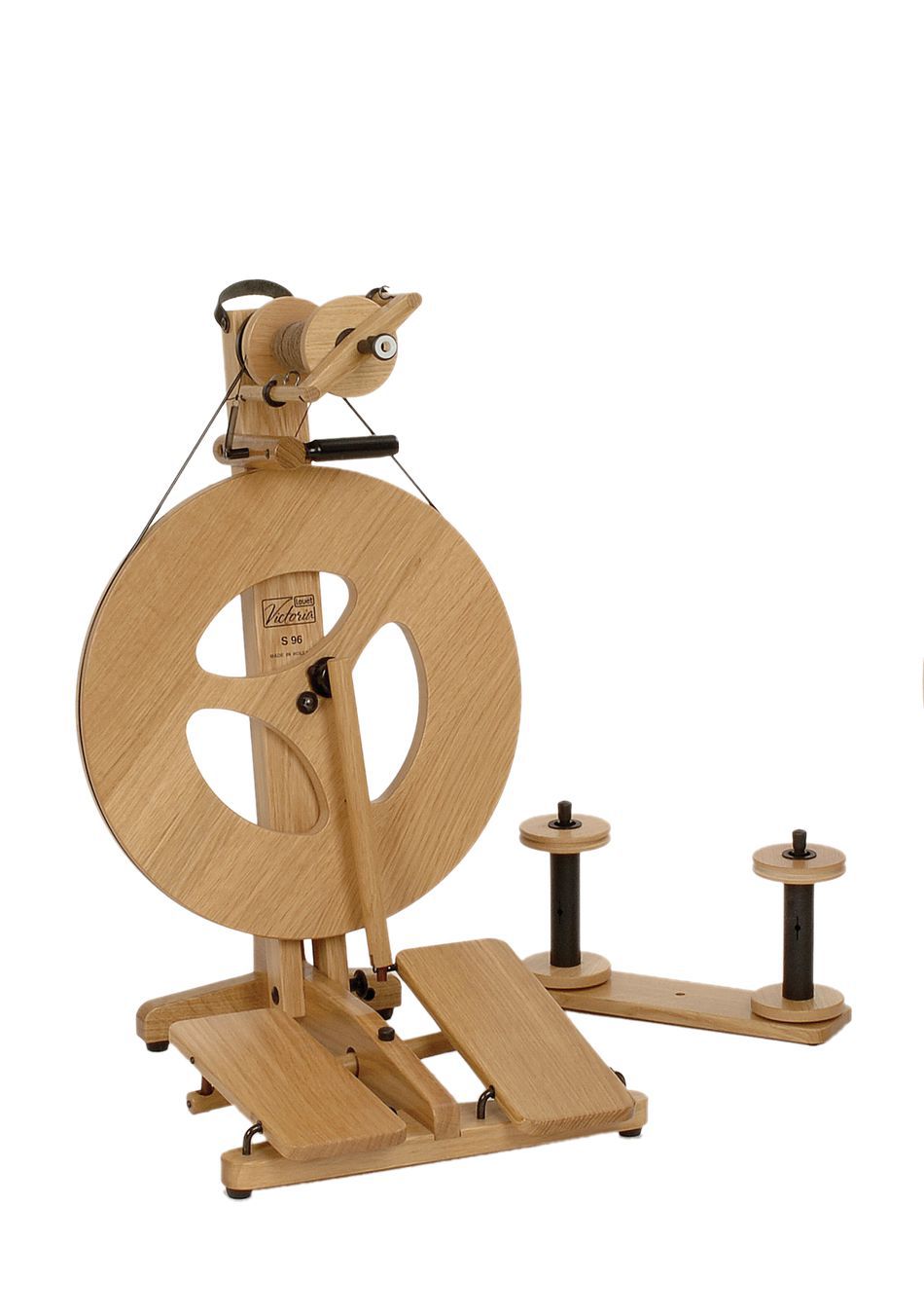 Introducing the Louët Victoria Double-Treadle Folding Spinning Wheel by Louët Inc. This exceptional spinning wheel features a wooden circular frame, double foot treadles, and a spindle for spinning yarn. It boasts a natural wood finish along with an adjustable bobbin brake for ease of use. Additionally, the design includes two extra spindles attached to the base beside it.