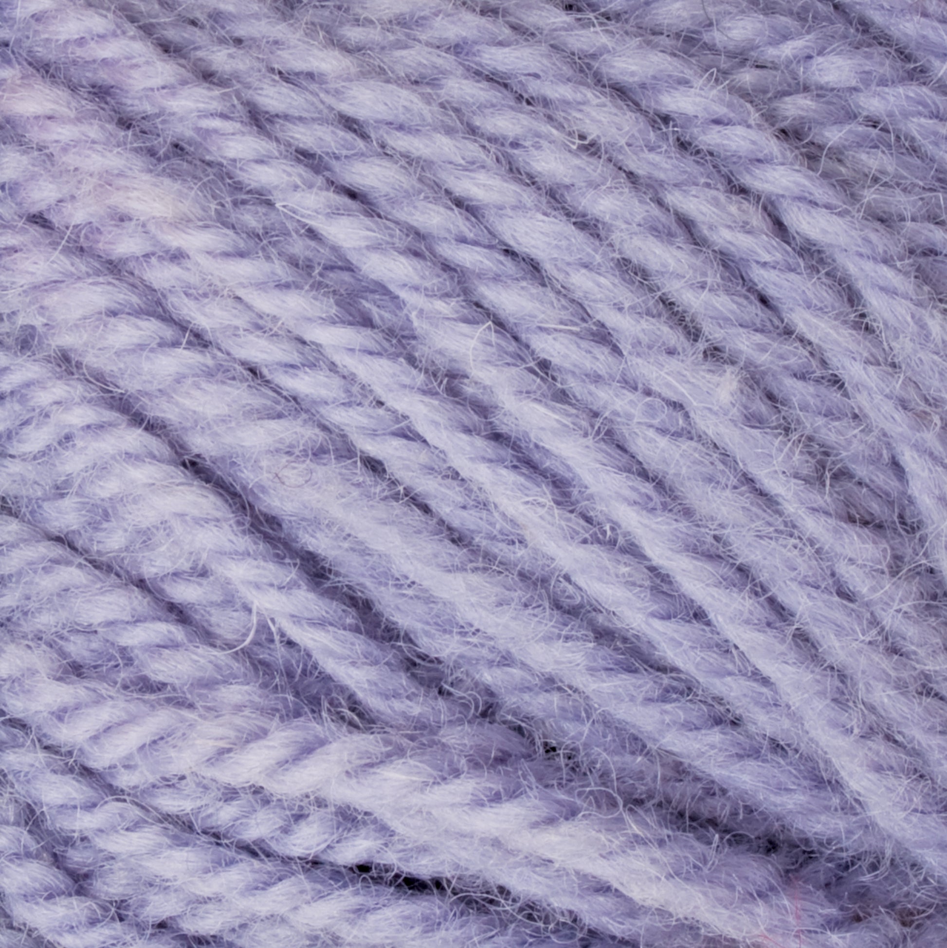 Close-up of soft, light purple Halcyon Deco Rug Wool by Caledonian Dye Works, showcasing its twisted, woolen texture. The strands are thick, fluffy, and slightly fuzzy, indicating a cozy fabric when knitted or crocheted. Made from 100% wool, this versatile yarn has a uniform and slightly cloudy color perfect for any project.