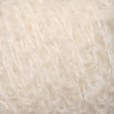 Close-up view of soft, white, textured yarn with a fluffy and lightly curled appearance. The fibers are intertwined, showcasing a delicate and cozy look reminiscent of Caledonian Dye Works' Signature Victorian Bouclé Mohair Yarn, commonly used for knitting or crocheting warm garments and accessories.