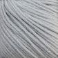 Close-up shot of light gray Baby Blatt yarn strands by Essentially Felt Studio & Fine Yarn, tightly wound together, showing a soft and fluffy texture. The fibers are neatly aligned, creating a smooth and uniform appearance suitable for knitting or crocheting projects. This fingering weight yarn is also machine washable for easy care.