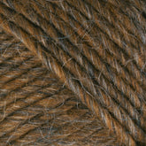 Close-up view of brown wool yarn from Brown Sheep's Lamb's Pride Worsted Yarn, with a blend of lighter and darker strands, showcasing the texture and interwoven fibers, perfect for felting projects.