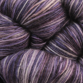 Close-up of a skein of Malabrigo Lace by Malabrigo Yarn, featuring a soft blend of purples, pinks, and subtle hints of white. The merino wool fibers are tightly twisted, accentuating the texture and seamless color transitions. The yarn appears soft and is ideal for creating knitted shawls or other crocheting projects.