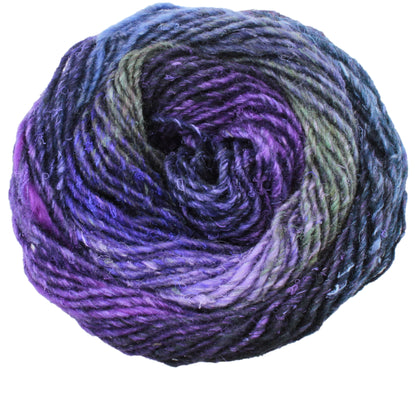 A close-up image of a ball of Noro Silk Garden yarn from Knitting Fever / Euro Yarns, showcasing an array of purple, blue, and green hues. This multi-color self-striping yarn is tightly twisted and has a textured appearance, with the colors blending seamlessly into one another.