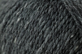 Close-up image of dark gray Jo Sharp Silkroad DK Tweed yarn from Kingfisher Yarn & Fibre, showcasing its soft and slightly fuzzy surface. The yarn appears dense and tightly spun, with subtle variations in shade that add depth to the monochromatic color.