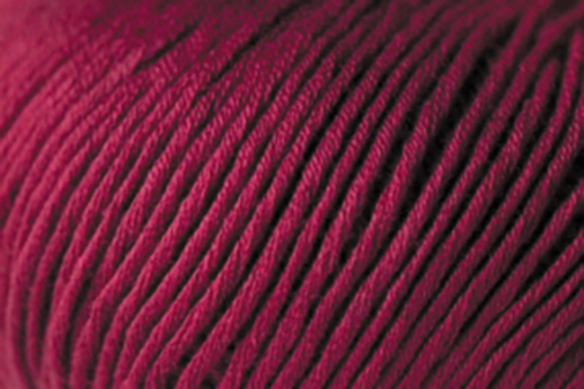 A close-up image of tightly wound, maroon-colored Jo Sharp Soho Summer DK Cotton Yarn from Kingfisher Yarn & Fibre, showcasing the texture and strands of the fiber. The yarn appears smooth and is closely packed in circular patterns, suggesting it is part of a larger skein or ball.