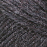 Close-up image of the Lamb's Pride Worsted Yarn by Brown Sheep, featuring a dark brown textured yarn with interwoven strands of gray and white fibers that create a varied and rich pattern throughout. Ideal for felting projects, the fibers appear soft, slightly fuzzy, and tightly twisted.