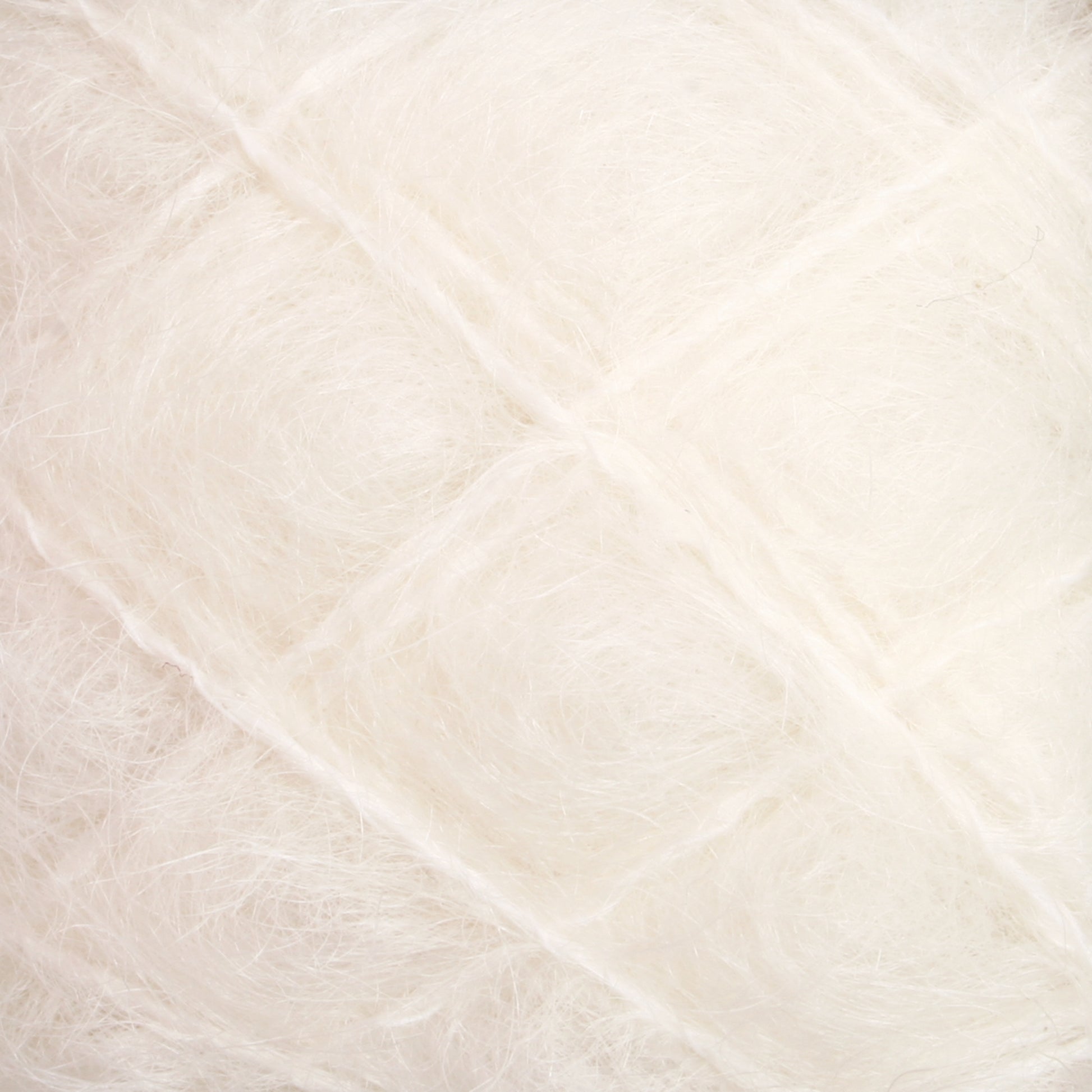 Close-up of soft, white Victorian Brushed Mohair Yarn from Caledonian Dye Works, featuring a textured surface with visible fine strands arranged in a slightly crisscross pattern. The material appears fluffy and delicate, reminiscent of luxurious mohair from yesteryear.