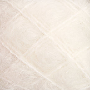 Close-up of soft, white Victorian Brushed Mohair Yarn from Caledonian Dye Works, featuring a textured surface with visible fine strands arranged in a slightly crisscross pattern. The material appears fluffy and delicate, reminiscent of luxurious mohair from yesteryear.