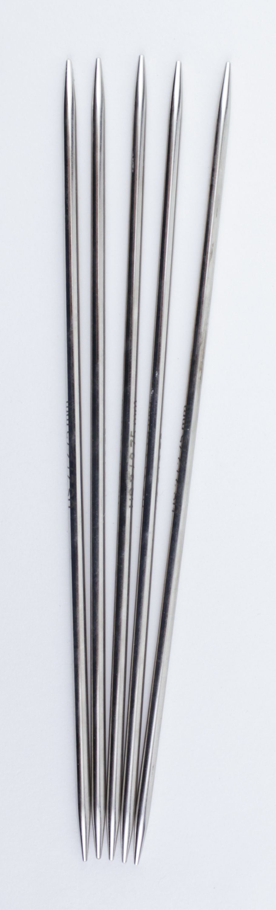 Five straight, double-pointed, high-quality chrome knitting needles are arranged vertically on a plain white background. The Accessories Unlimited Nova Platina Double-Point Knitting Needles are evenly spaced and aligned parallel to each other.