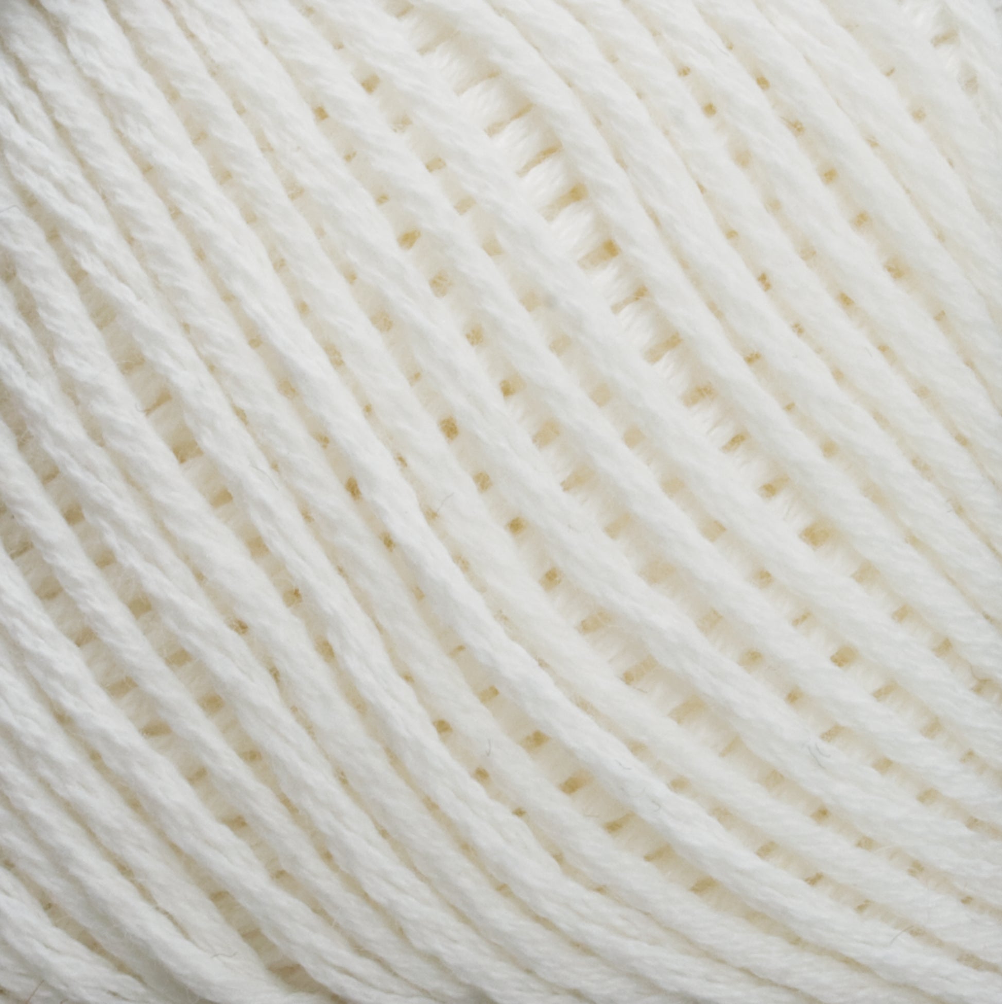 Close-up view of Brown Sheep's Cotton Fleece, showcasing its texture and the individual strands woven together. The yarn appears soft and fluffy, making it perfect for knitting or crocheting intricate patterns.