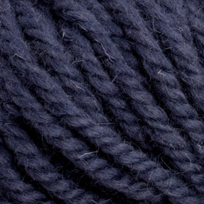 Close-up image of Halcyon Yarn Classic Rug Wool by Caledonian Dye Works, in a rich dark blue hue twisted into thick strands. The texture of the skein appears soft and slightly fuzzy, with individual fibers visible. The background is entirely filled with the intertwined strands, creating a dense, woven pattern that is sure to enchant weavers and hand-dye enthusiasts alike.