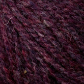 Close-up of dark purple and maroon Bartletts Maine Wool - Sport yarn from Bartlettyarns, highlighting the intricate, interwoven fibers and slightly fuzzy texture. The strands showcase a mix of deep, rich hues blended with subtle lighter threads, emphasizing the sport weight yarn's soft and detailed composition.