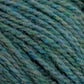 Close-up of Harrisville Designs' Harrisville Highland - Cones yarn in green and blue speckles. The unscoured yarn fibers appear textured and tightly wound, showcasing the intertwined strands and subtle variations in color, creating a rich and intricate pattern.