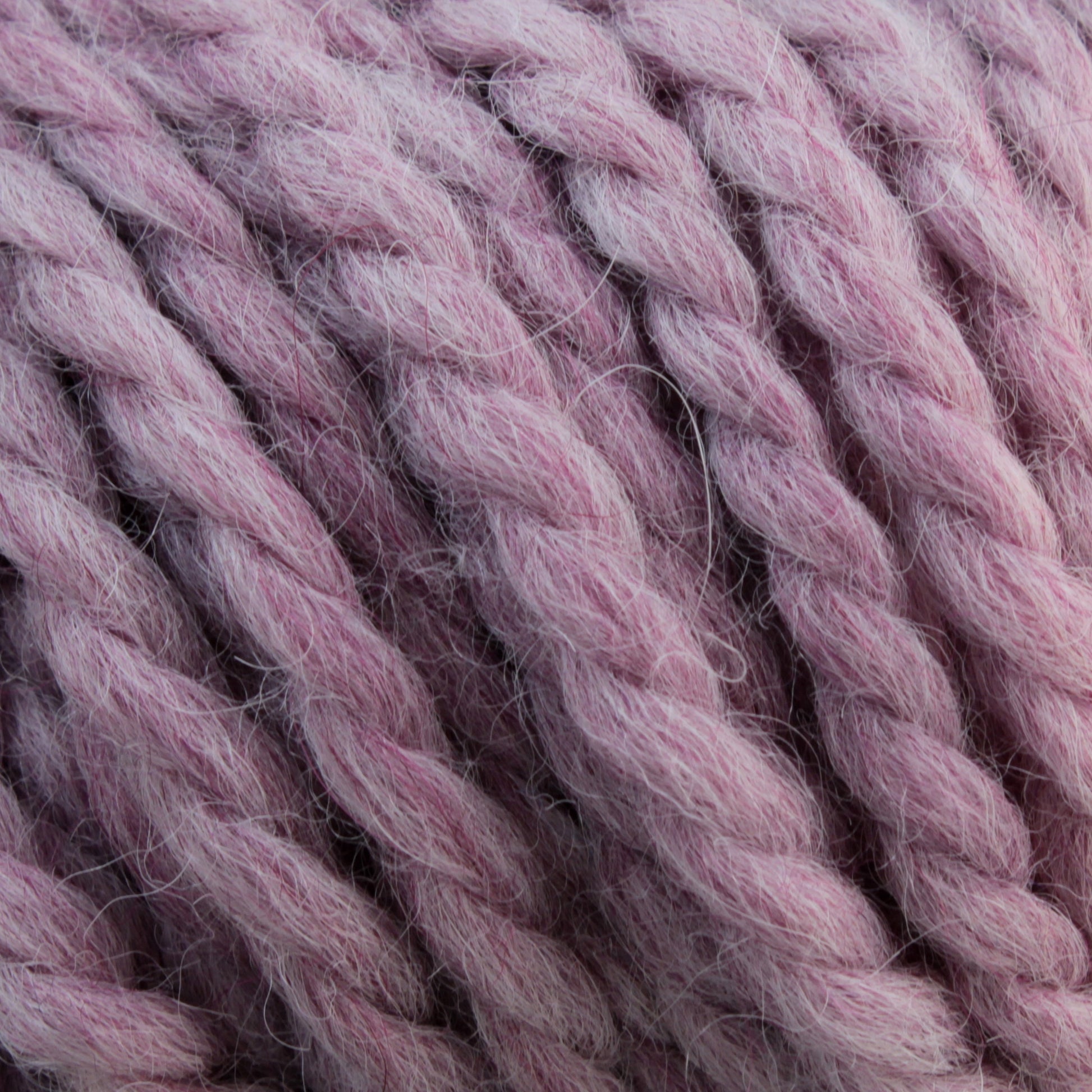 Close-up of bulky, twisted Baby Alpaca Grande by Plymouth in a soft pink color. The ultra-soft fibers give it a slightly fuzzy texture, making it thick and perfect for cozy, chunky knitting or crochet projects.