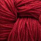 Close-up image of thick, soft strands of Malabrigo Rios by Malabrigo Yarn, tightly coiled together. The yarn exhibits a smooth texture with rich, vibrant red color, showcasing visible twists and fibers enhanced by kettle-dyed hues that create a detailed and tactile visual.