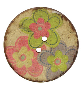 The Coconut Multi Flower 1 1/2" Button by Skacel is a round, vintage-style, two-hole button with a worn beige surface. This charming button features a colorful floral design with overlapping flowers in shades of green, pink, purple, and yellow. Made from painted coconut shell buttons, its lightweight nature and slightly chipped edges indicate age and wear.