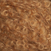 Close-up view of tightly wound, curly golden-brown yarn fibers intertwined in a soft, textured pattern. The curls give the yarn a fluffy and voluminous appearance. This texture suggests it could be used for knitting or crafting projects within Caledonian Dye Works' Signature Victorian Bouclé Mohair Yarn Collection.