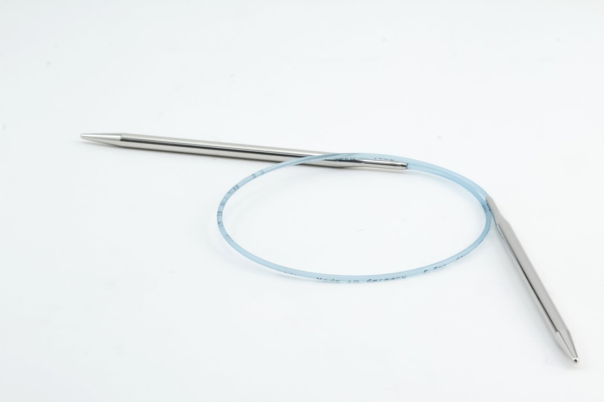 A pair of Addi Turbo Circular Knitting Needles by Skacel is displayed on a white background. The needle tips are metallic and connected by a flexible blue cable, forming a circular shape perfect for knitting cuffs, collars, or doll clothes.