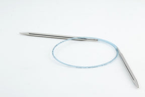 A pair of Addi Turbo Circular Knitting Needles by Skacel is displayed on a white background. The needle tips are metallic and connected by a flexible blue cable, forming a circular shape perfect for knitting cuffs, collars, or doll clothes.