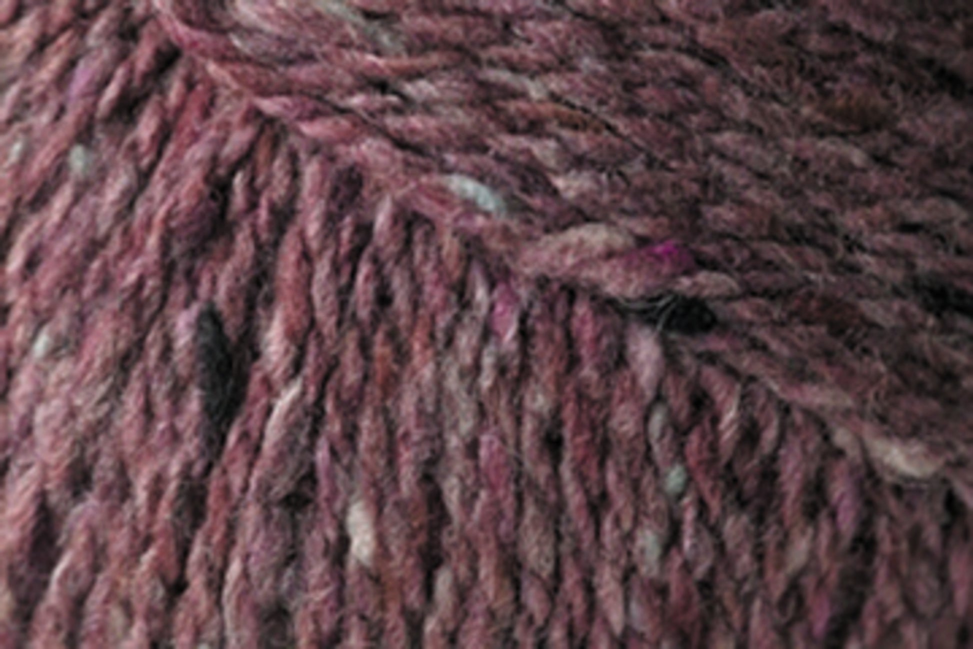 Close-up of Kingfisher Yarn & Fibre's Jo Sharp Silkroad DK Tweed yarn, featuring a blend of deep burgundy and lighter fibrous strands, creating a marled appearance. This DK weight yarn appears thick and soft, making it ideal for knitting warm garments.