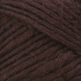 Close-up image of Lamb's Pride Bulky Yarn by Brown Sheep, showcasing the texture and strands tightly wound together in a dark brown hue. The fibers appear soft and slightly fuzzy, with a rich, deep color. Perfect for knitters and crocheters, the image highlights the intricate details and uniformity of the yarn's thickness.