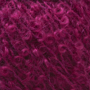 Close-up image of tightly curled, magenta-colored hair or fibers. The curls are densely packed, creating a textured and voluminous appearance. The vibrant magenta hue is consistent throughout, giving the material a rich, colorful look reminiscent of Caledonian Dye Works' Victorian Bouclé Mohair Yarn.