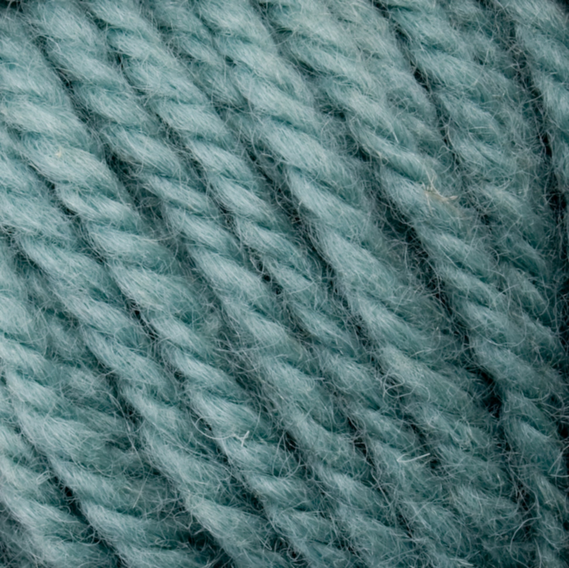 Close-up of the Halcyon Yarn Classic Rug Wool in a rich teal hue, showcasing its visible fibers and twisted texture. Hand-dyed by Caledonian Dye Works, this yarn features tightly wound strands that highlight its detailed and textured appearance, making it perfect for weavers.