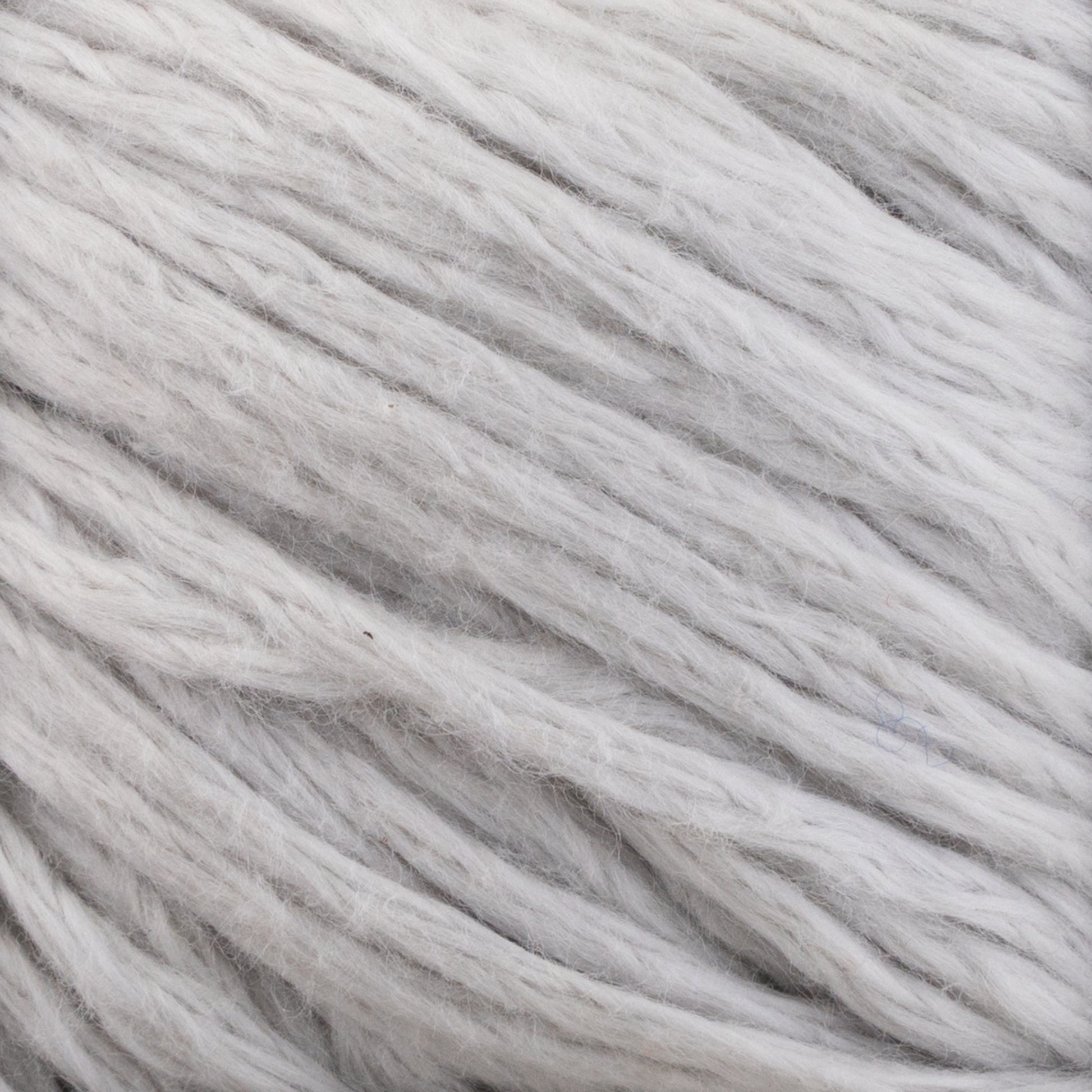 Close-up image of thick, soft white Cumulus Cotton yarn fibers by Juniper Moon Farm, loosely twisted together. The texture appears fluffy and smooth, with slight variations in shades of white and light gray throughout. This soft yarn from Knitting Fever / Euro Yarns, featuring durable chainette construction, looks cozy and suitable for knitting or crafting.