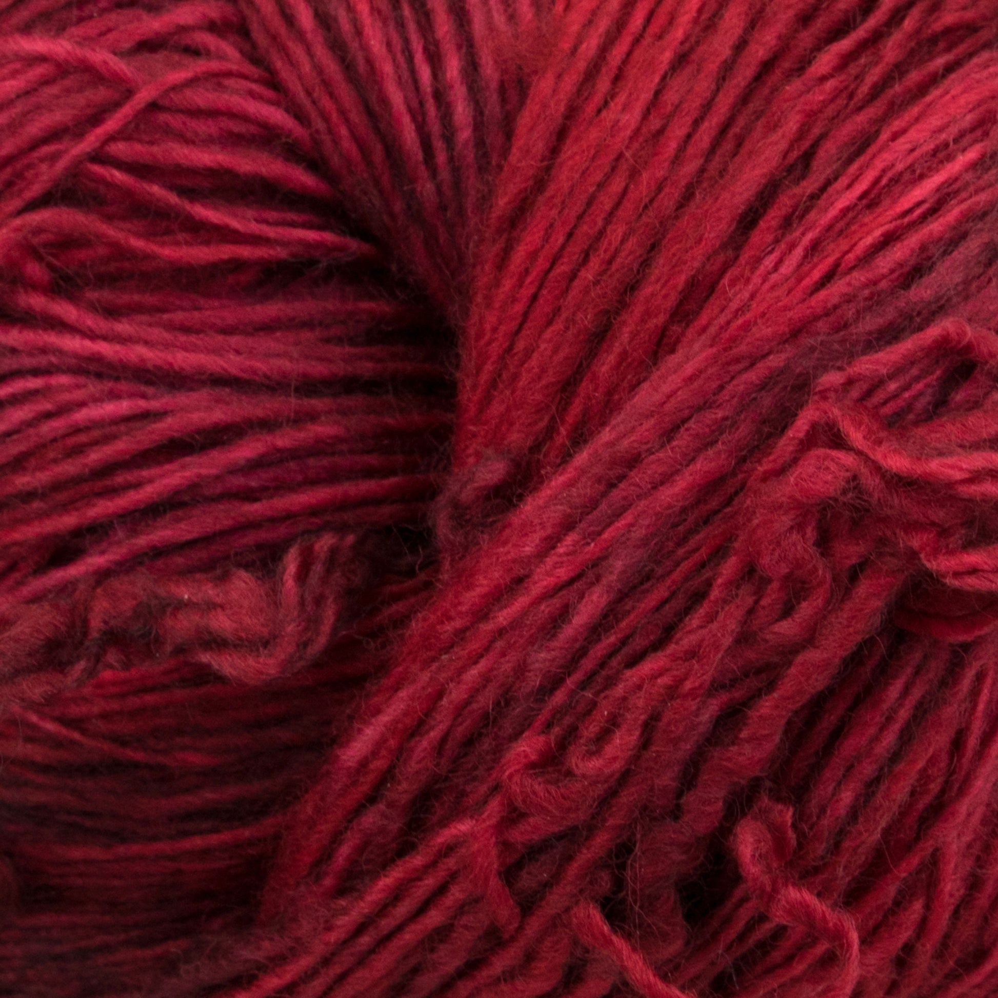 Close-up image of a ball of Malabrigo Lace from Malabrigo Yarn, showcasing its soft texture and vibrant color variations, with strands loosely coiled together. The yarn appears thick and plush, ideal for knitting or crocheting cozy garments or accessories like luxurious knitted shawls.