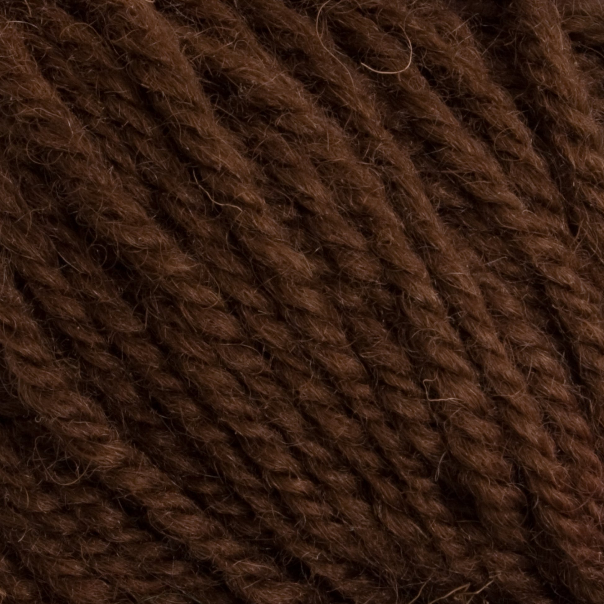 Close-up of brown Halcyon Deco Rug Wool by Caledonian Dye Works, showing its texture and twisted fibers, highlighting the detailed strands of this 100% wool.