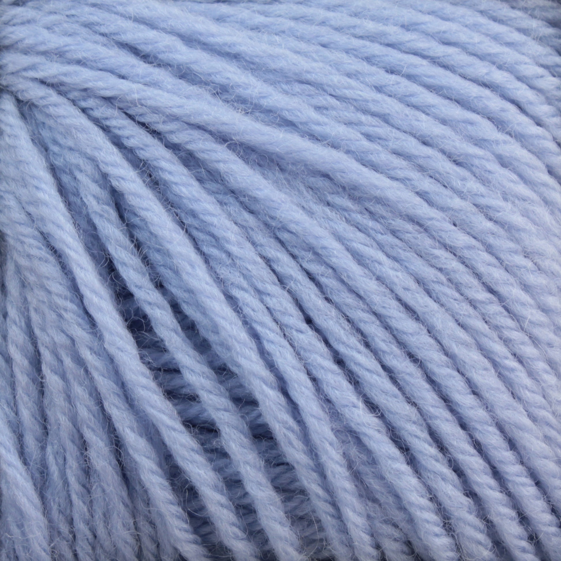 Close-up image of Baby Blatt by Anny Blatt, a soft, light blue baby yarn from Essentially Felt Studio & Fine Yarn. The strands are wound together, creating a textured pattern with visible fibers and slight variations in thickness. This thick and plush yarn is perfect for knitting or crocheting cozy, warm projects and is ideal for machine washable items.