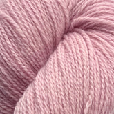 Close-up image of tightly wound light pink yarn made from Patagonia Organic Merino by Juniper Moon Farm. The texture of the yarn is visibly soft, thick, and slightly fuzzy, showcasing its fibrous nature. The yarn has a gentle sheen which adds a subtle depth to its pastel hue. This luxurious yarn is offered by Knitting Fever / Euro Yarns.