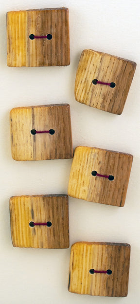 Six rectangular handcrafted buttons from Favour Valley Woodworking, each with two holes for sewing, are arranged casually in a diagonal pattern on a plain, light-colored background. The intricately designed buttons feature a natural wood grain pattern with slight variations and some darker shading, highlighting their unique appeal.