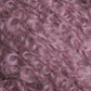 Close-up of a textured, fluffy pink yarn with curly fibers. The Victorian Bouclé Mohair Yarn, part of Caledonian Dye Works' Signature Victorian Collection, has a soft appearance, with tightly coiled loops giving it a fuzzy and voluminous look.