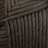 Close-up of thick, dark gray Lamb's Pride Bulky Yarn wrapped in horizontal and diagonal layers, showing the texture and fibers of the material. The Brown Sheep yarn appears chunky and soft, ideal for knitters and crocheters creating cozy woven blankets or Icelandic sweaters.