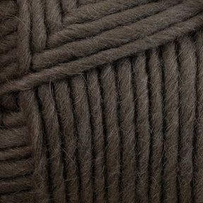 Close-up of thick, dark gray Lamb's Pride Bulky Yarn wrapped in horizontal and diagonal layers, showing the texture and fibers of the material. The Brown Sheep yarn appears chunky and soft, ideal for knitters and crocheters creating cozy woven blankets or Icelandic sweaters.