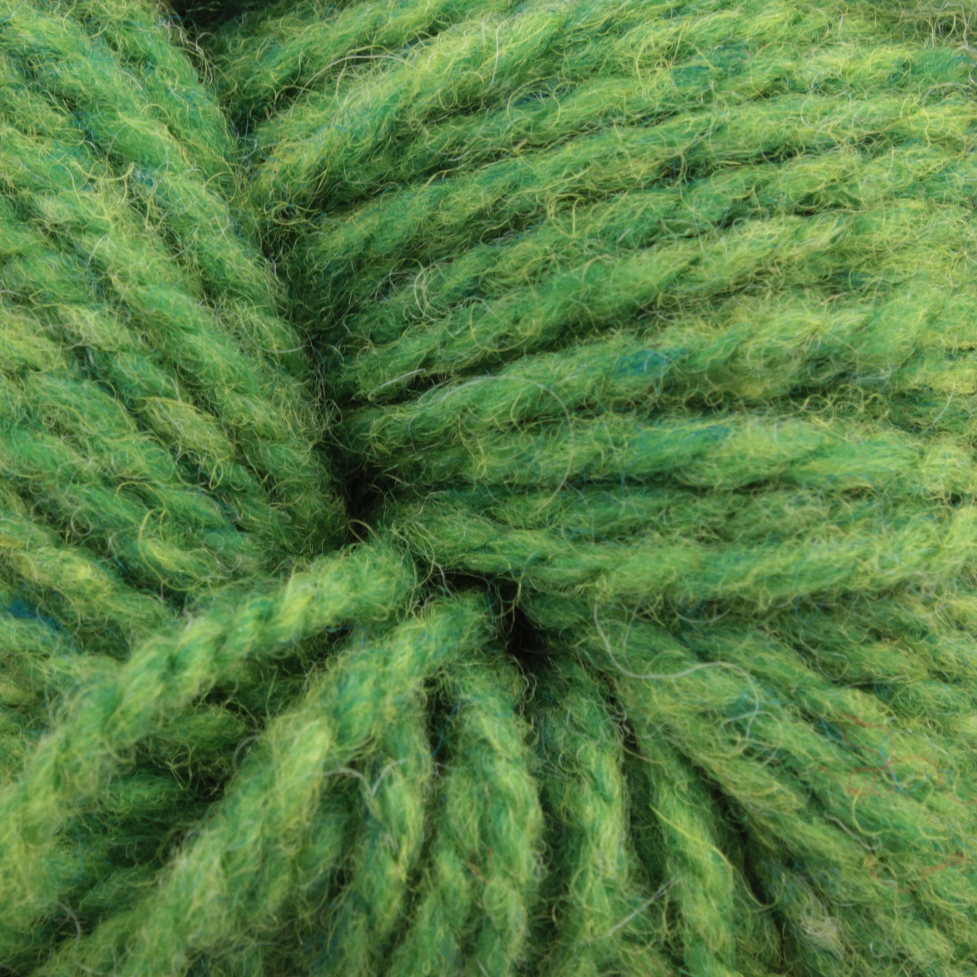 Close-up image of Bartlettyarns Maine Wool Yarn in a green worsted weight intertwined, textured pattern. The yarn, by Bartlettyarns, has a soft and slightly fuzzy appearance with various heathered shades of green that create depth and contrast.